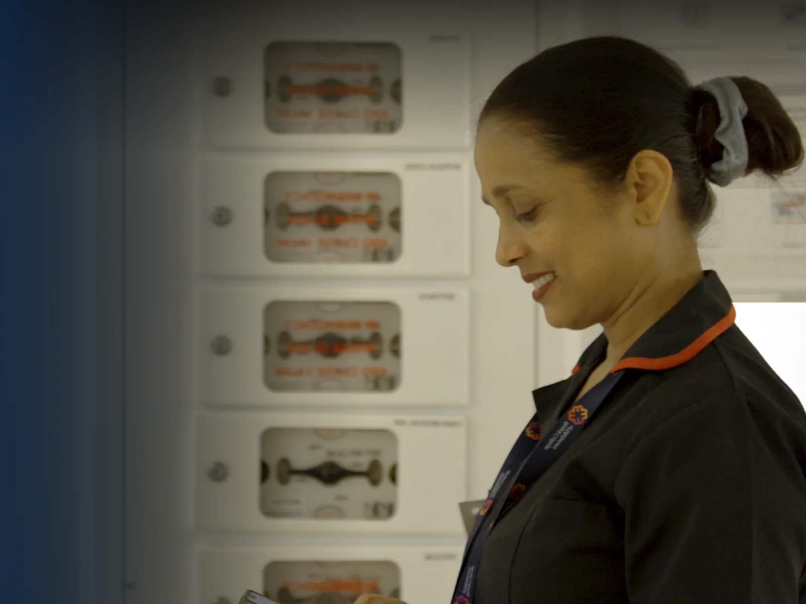 A nurse reading a governed document on her phone at a ward equipment station